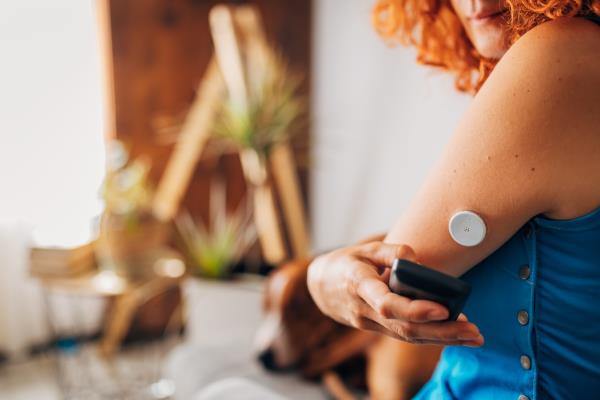 A close up of a person using a diabetes reader near a port in their left arm