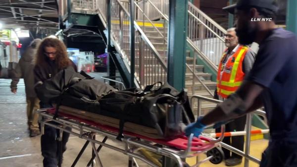 Off-duty MTA workers at the scene of a subway surfing incident at 111 St & Roosevelt Ave, wher<em></em>e 2 teenage girls were injured and 1 died. A person on a stretcher with a bag is visible.