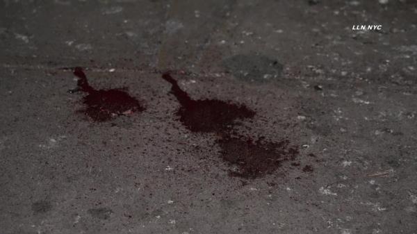 Off-duty MTA workers standing at 111 St & Roosevelt Ave, near traces of a subway incident involving teen girls, with visible sneakers and blood on the tracks