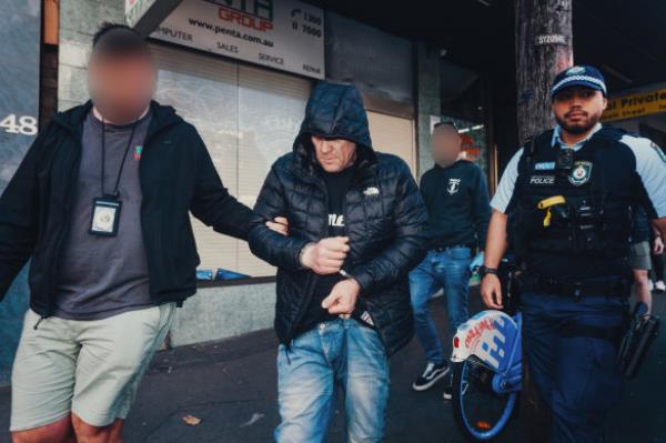 Peter Taylor is taken to a police van after being arrested in a Sydney CBD hotel.