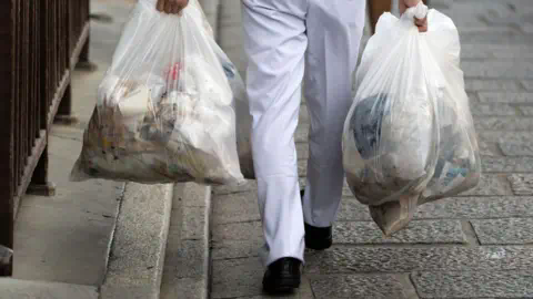 Getty Images A man carrying garbage bags 