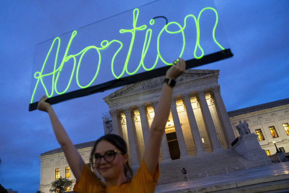 An activist marks the first anniversary of the Supreme Court’s decision that overturned Roe v Wade, by displaying a neon sign in support of abortion access in front of the US Supreme Court.